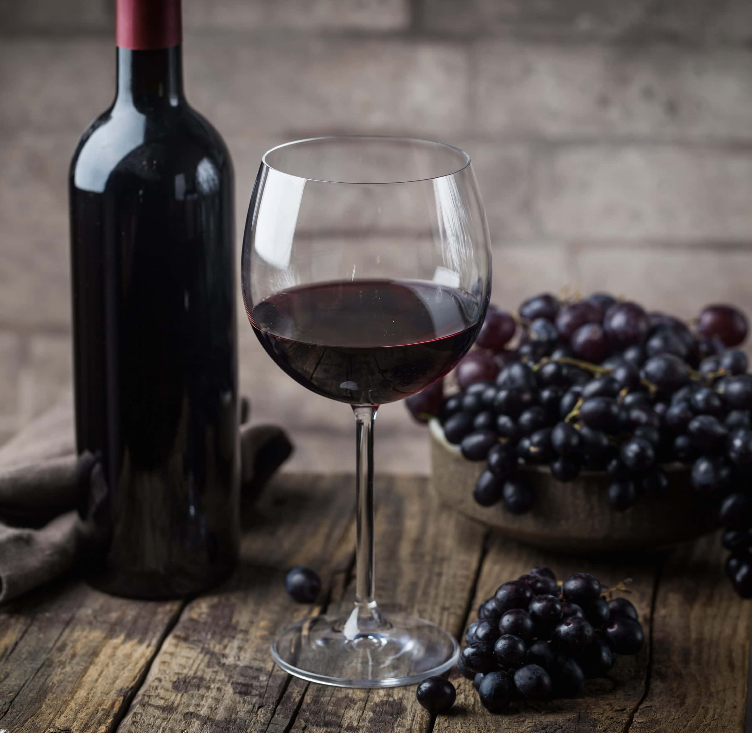 Red Wine and Grapes – Classic Pairing for French Cuisine Glass of red wine next to a bunch of red grapes – rich, full-bodied wine used in French cooking and classic recipes like Coq au Vin