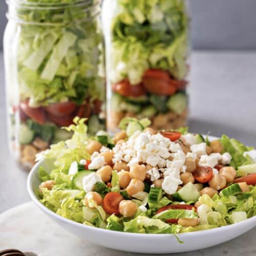 Layered Greek salad in a mason jar with chickpeas, feta cheese, and vegetables – a healthy Mediterranean meal prep lunch idea
